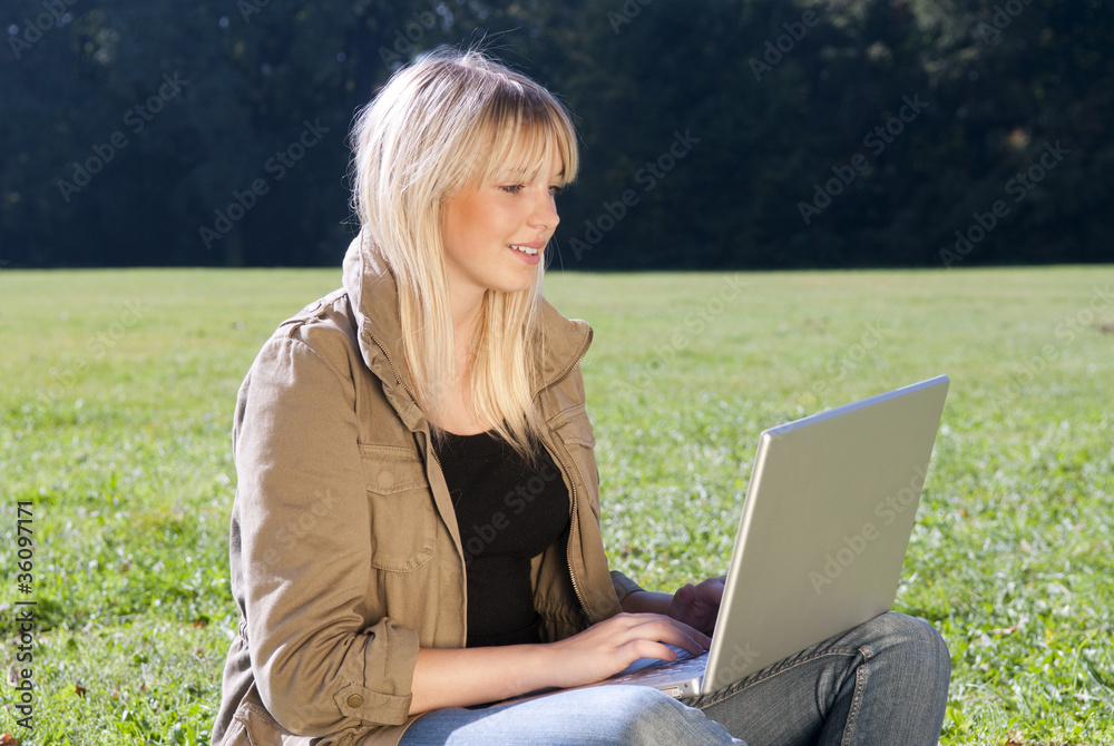 junge frau mit laptop auf einer wiese junge frau mit laptop auf einer wiese