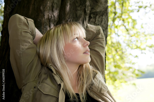 junge frau steht an einem baum