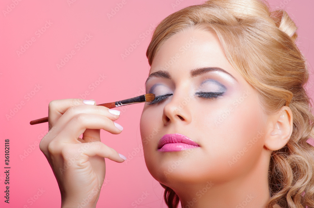 Beautiful woman applying cosmetic paint brush