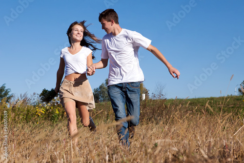Happy young couple running on summer meadow