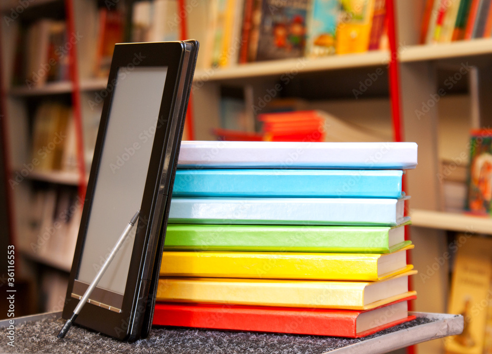 Stack of colorful books with electronic book reader