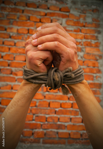 Obraz na płótnie Hands tied up with rope against brick wall w salonie