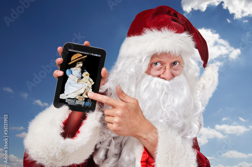 Santa Claus with antique doll on the tablet pc photo