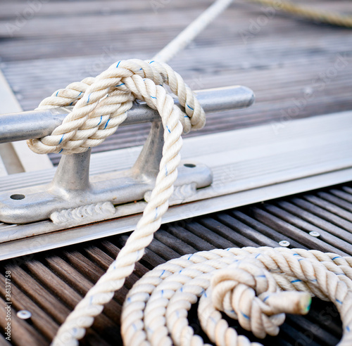 White mooring rope tied around steel anchor on boat or ship.
