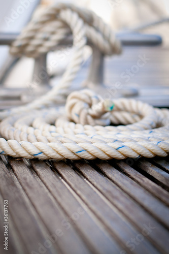 Mooring rope with a knotted end tied around a cleat on a pier.