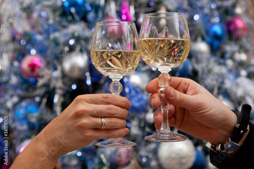 Hands holding glasses of champagne against new year tree