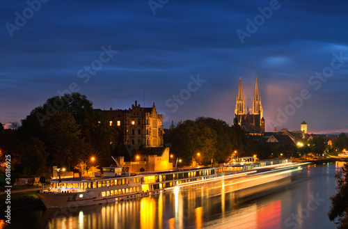 Regensburg  Donau mit Flusskreuzfahrtschiff bei Nacht mit beleuchtetem Dom 