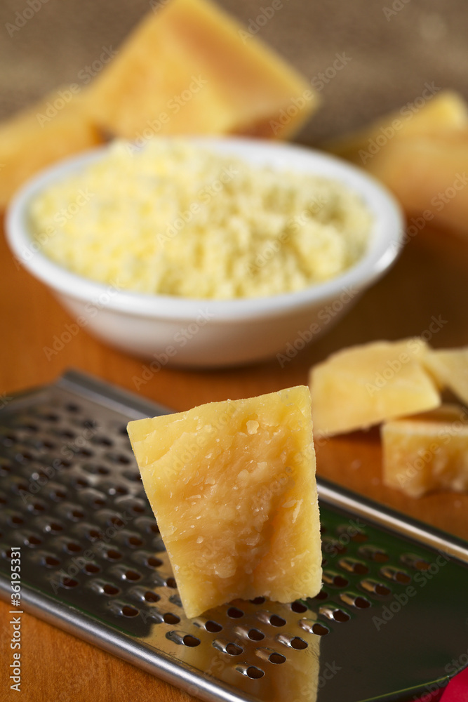 Italian hard cheese on rasp with grated cheese in back Italian hard cheese on rasp with grated cheese in back