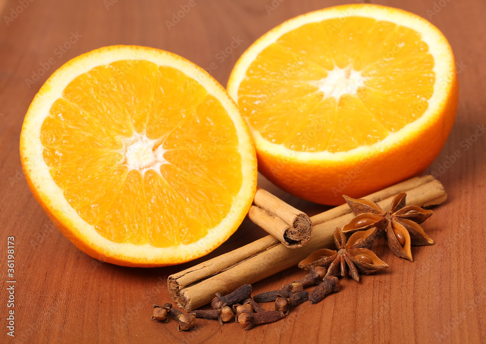 Orange mit Zimt, Anis und Nelken vor Holz Hintergrund Orange mit Zimt, Anis und Nelken vor Holz Hintergrund