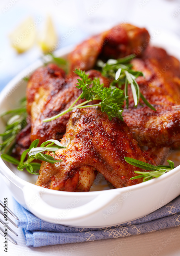 Roasted chicken wings with rosemary in a white dish Roasted chicken wings with rosemary in a white dish
