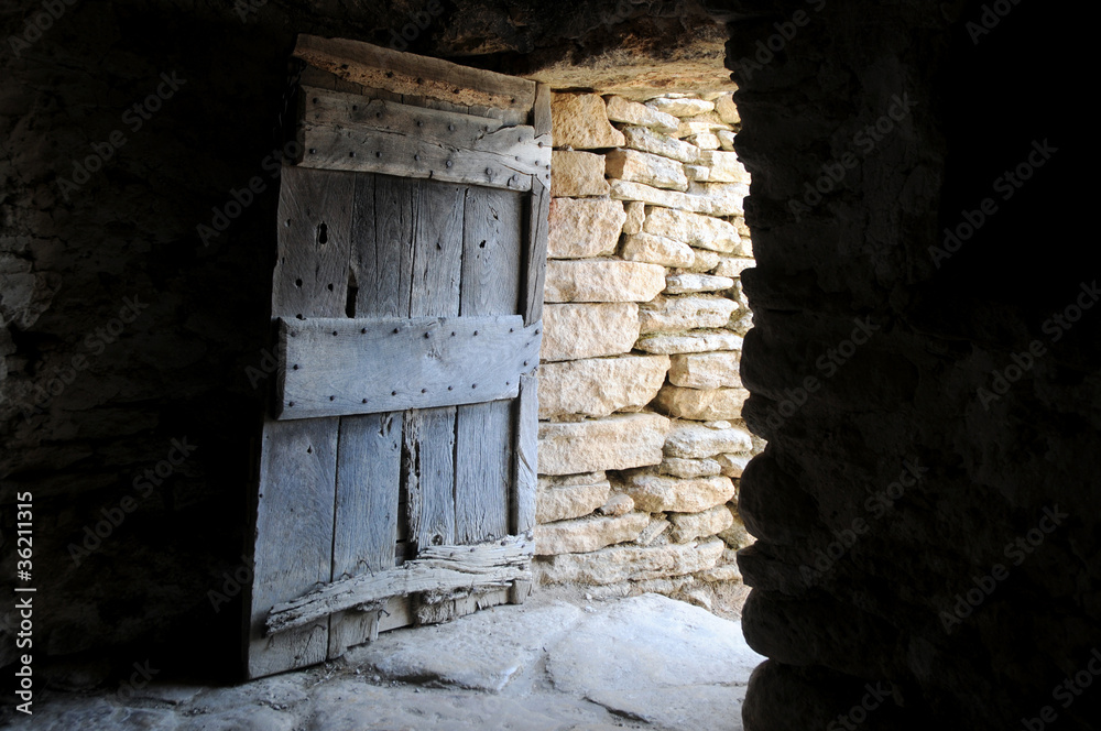 primitive wooden door in old stony hut