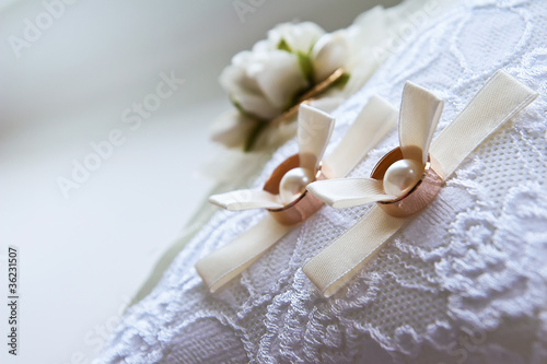 Two wedding rings with white flower in the background