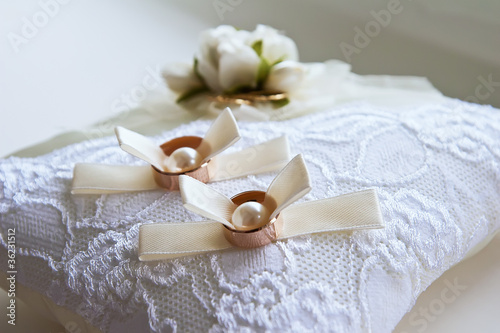 Two wedding rings with white flower in the background