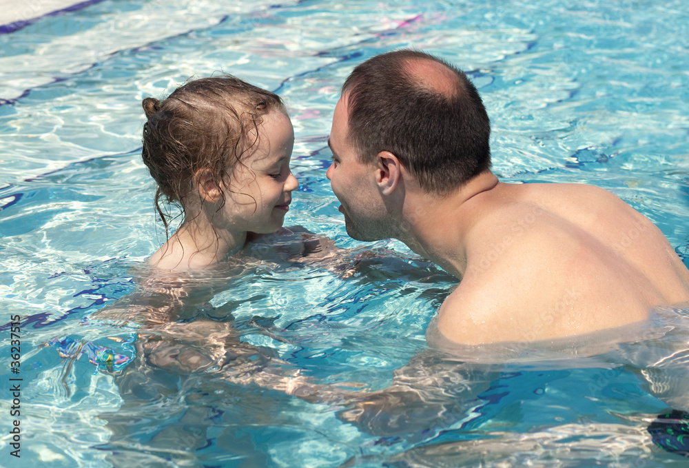 Joyful little girl with dad in the pool