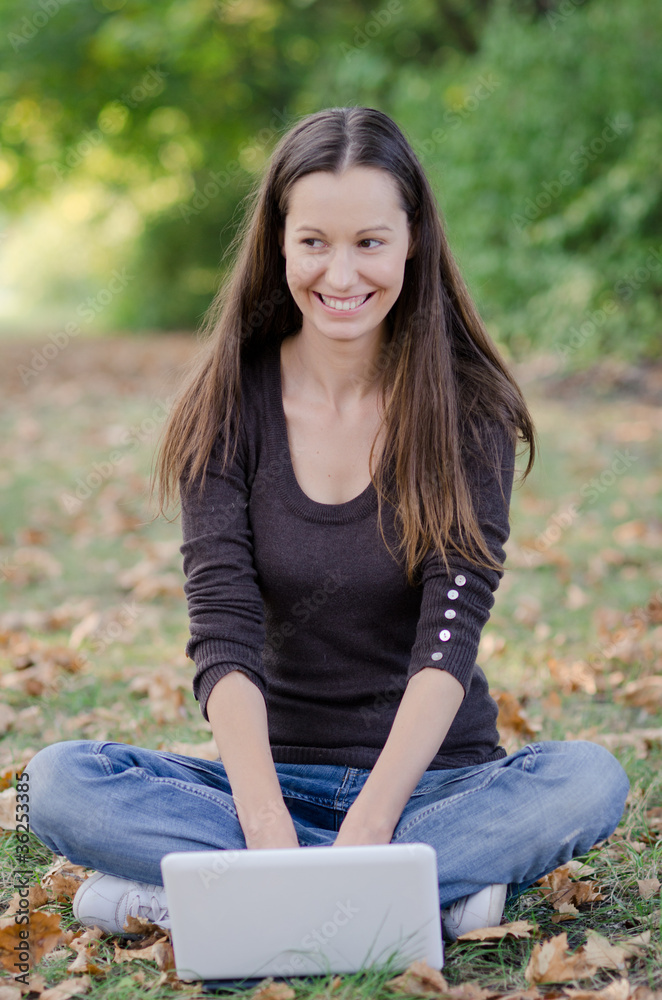 Girl sitting on the grass working on laptop at the park Girl sitting on the grass working on laptop at the park
