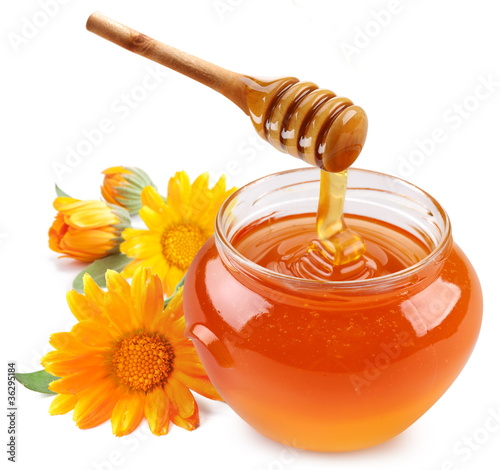 Honey pours with sticks in a jar. photo