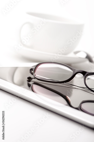 White tablet, coffee cup and glasses on a white table