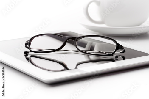 White tablet, coffee cup and glasses on a white table