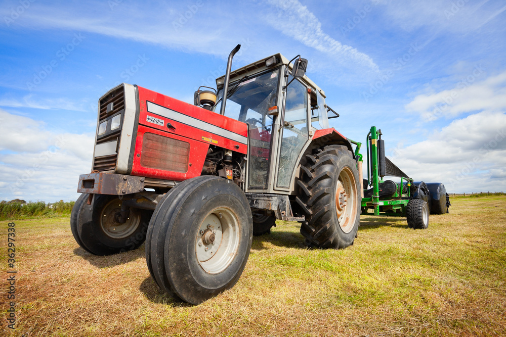 tractor collecting a roll of haystack in the field tractor collecting a roll of haystack in the field