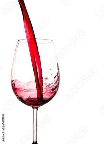 Red wine pouring into glass, isolated on white background