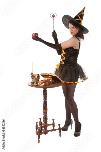 sexy girl in Halloween witch bewitches an apple photo