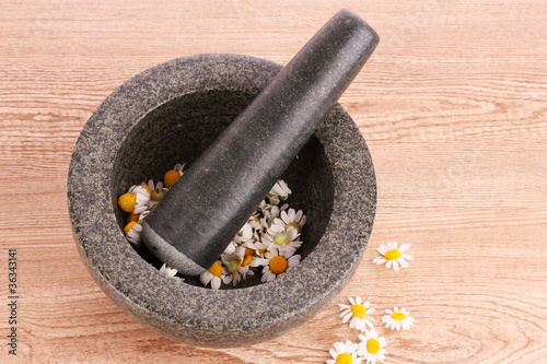 chamomile flowers in a mortar on brawn