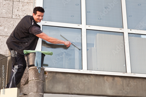 freundlicher gebäudereiniger putzt ein fenster photo