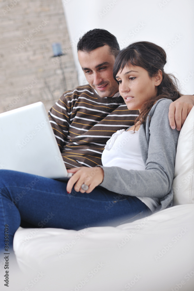 Fototapeta premium joyful couple relax and work on laptop computer at modern home