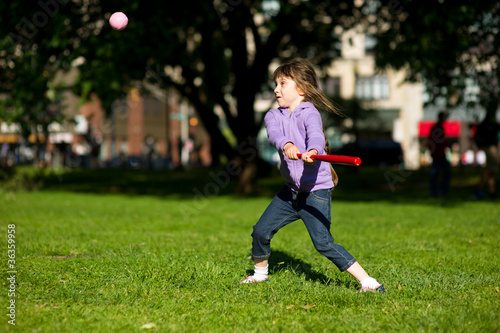 Child girl playing baseball in park