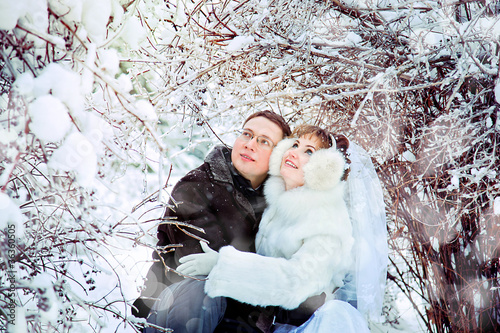 Bride and groom looking up under a frozen tree