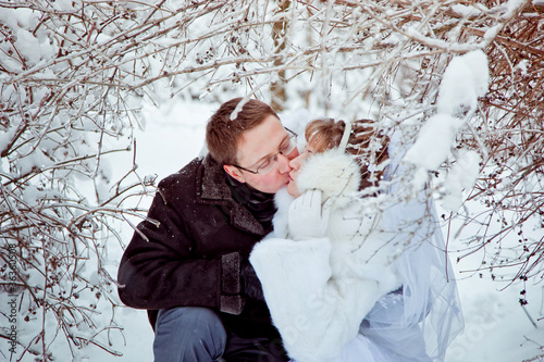 Bride and groom kissing under a frozen tree