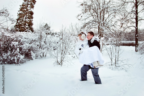 groom carries his bride in winter