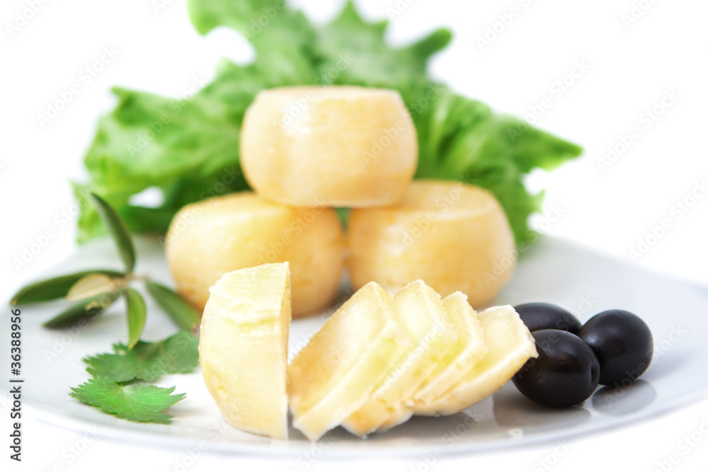 species of cheeses on a plate with black olives.