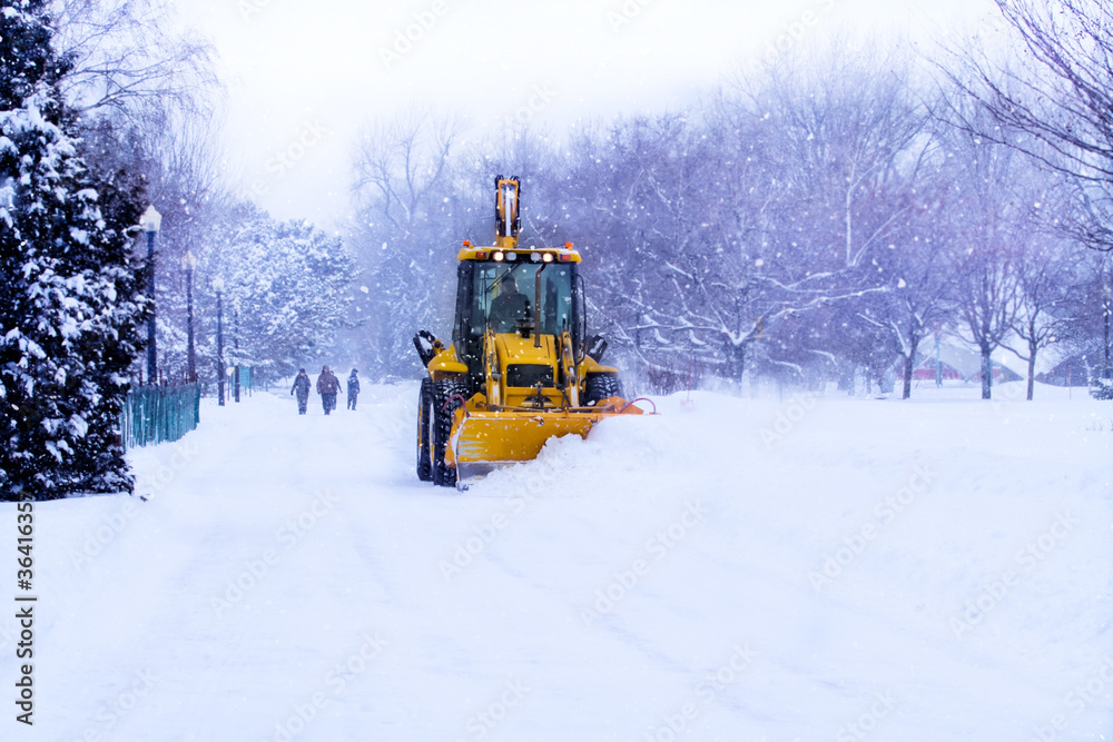 Snow plow clears the road during winter storm.