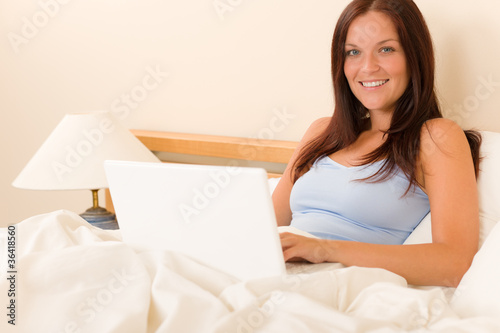 Beautiful woman working on computer in bed