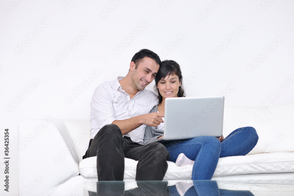 joyful couple relax and work on laptop computer at modern home joyful couple relax and work on laptop computer at modern home