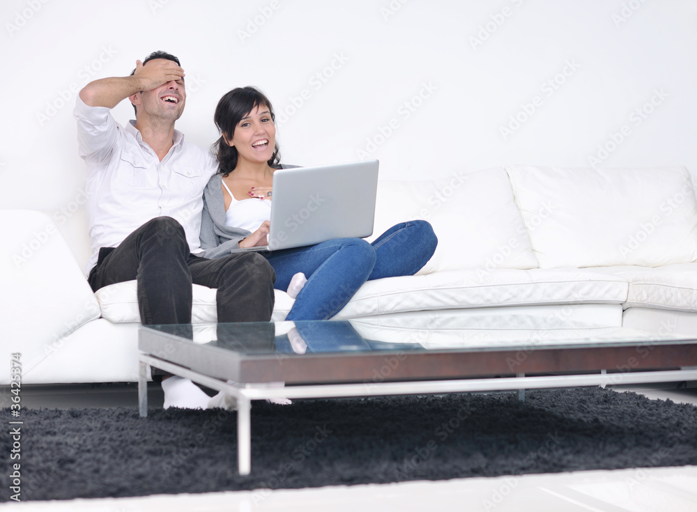 joyful couple relax and work on laptop computer at modern home joyful couple relax and work on laptop computer at modern home