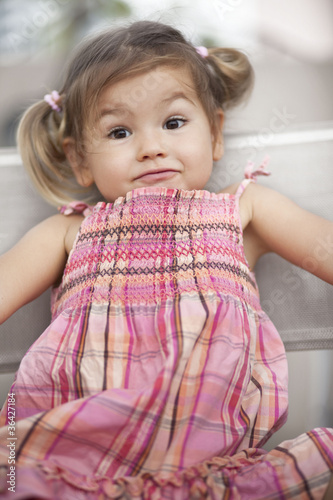 Obraz na płótnie Surprised baby with blond hair in a red dress, half-breed