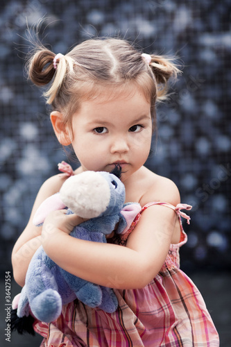 Bild auf Leinwand A little girl half-breed with a toy