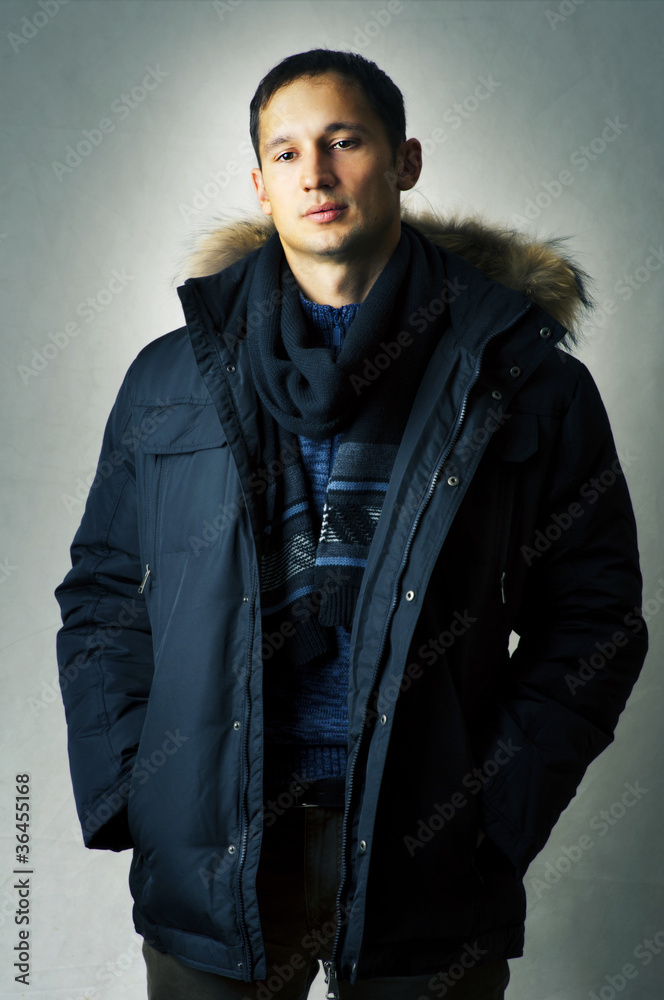 Fototapeta premium Sexy man in black fur hood winter jacket
