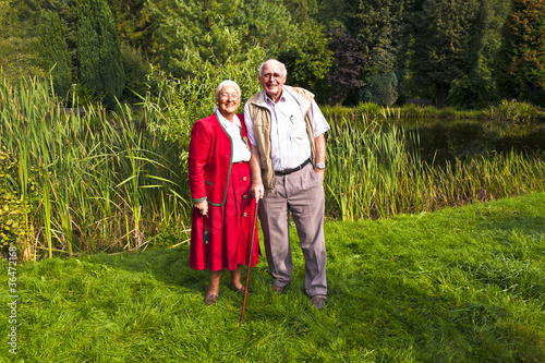 elderly couple standing hand in hand in their garden
