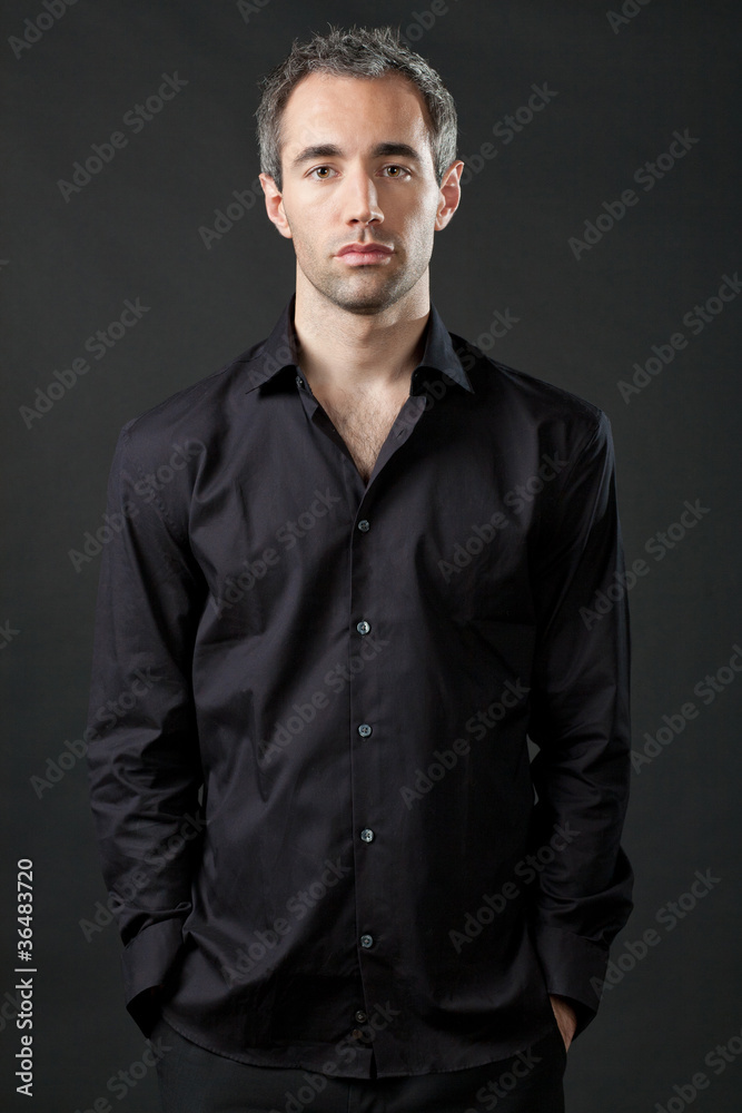 Obraz premium Handsome man posing in black shirt on dark background.