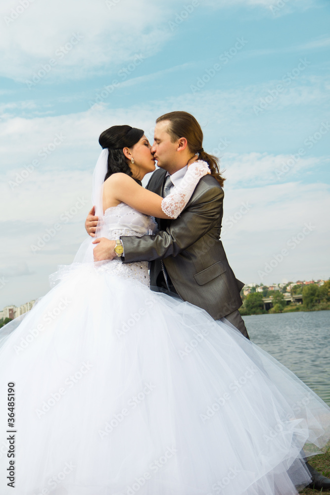 Happy bride and groom against blue sky