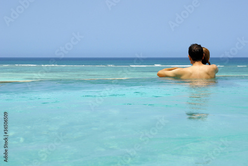 Young couple in a swimming-pool looking at the sea