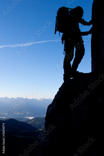 Silhouette of a climber high above valley