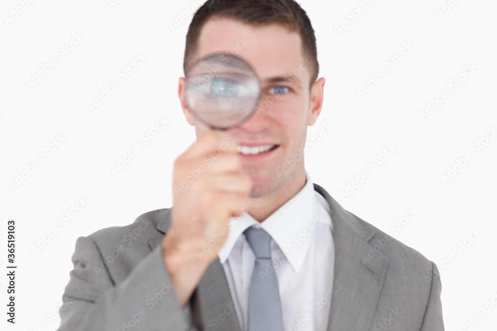 Young businessman looking through a magnifying glass Young businessman looking through a magnifying glass
