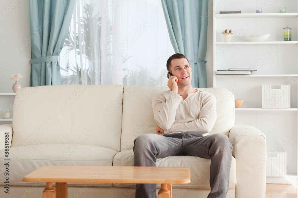 Man on the phone while sitting on his sofa Man on the phone while sitting on his sofa