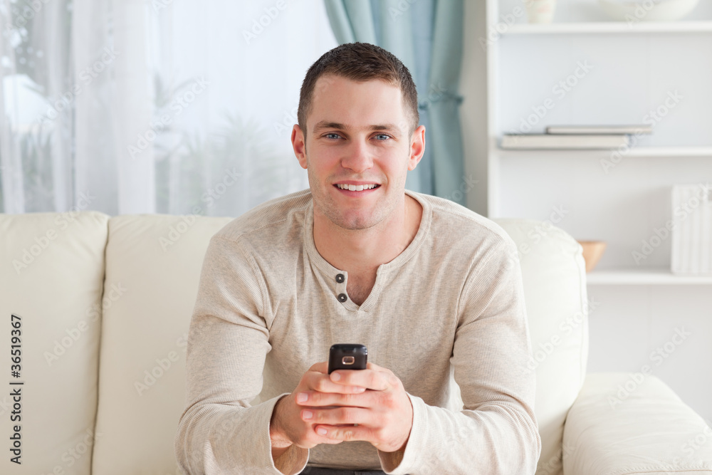 Man sending text messages while sitting on a sofa Man sending text messages while sitting on a sofa
