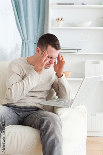 Portrait of a man having a headache while using a laptop