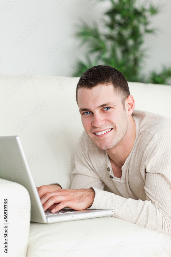 Portrait of a man lying on a sofa with a laptop Portrait of a man lying on a sofa with a laptop